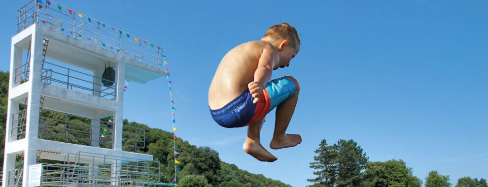 Kleiner Junge im Freibad springt ins Wasser