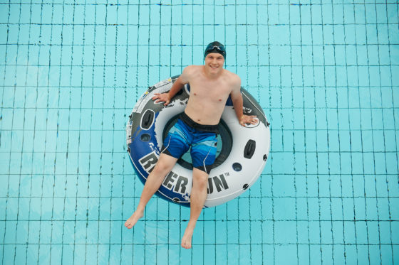 Sportlicher Badegast sitzt in einem Schwimmreifen