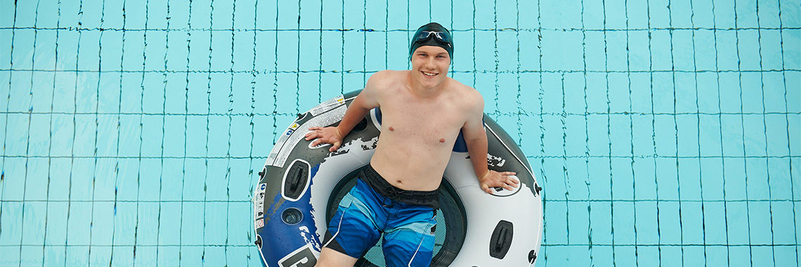 Sportlicher Badegast sitzt in einem Schwimmreifen