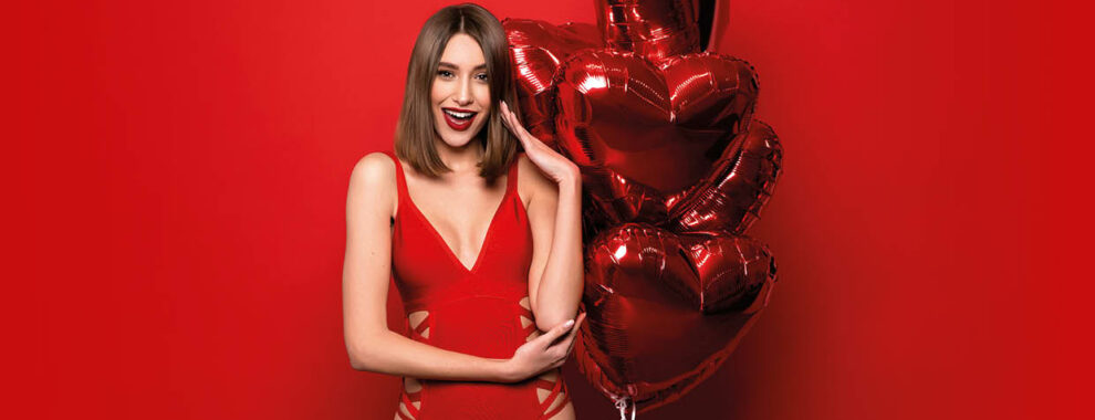 Frau im roten Badeanzug mit Herzluftballons